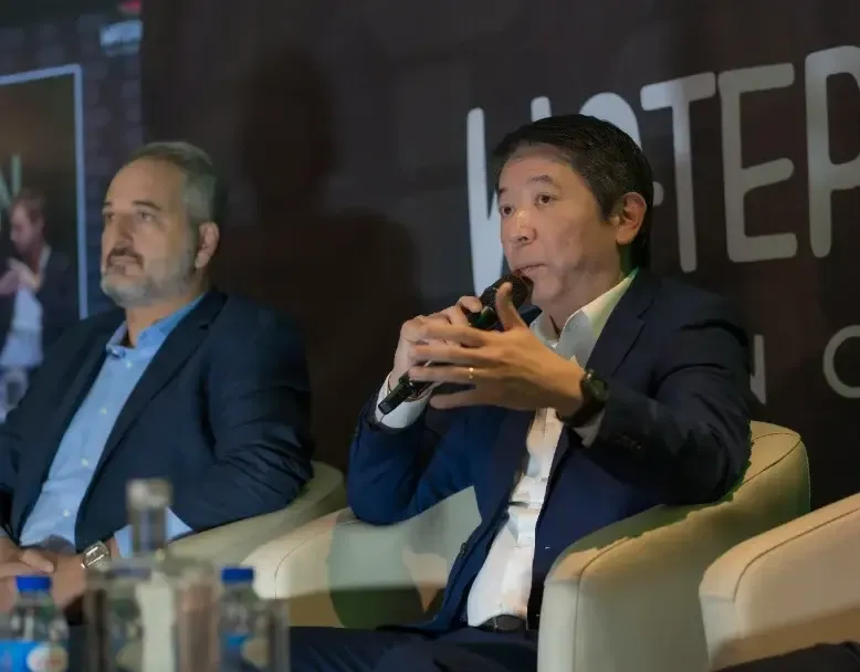 Dos panelistas en el escenario; uno habla al micrófono