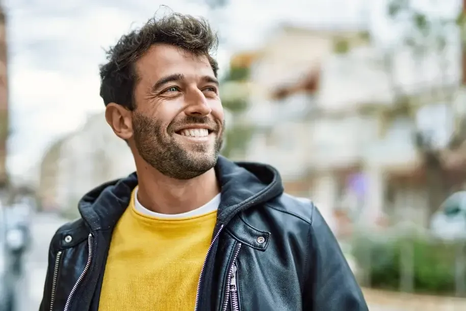 Hombre sonriente con chaqueta de cuero, al aire libre