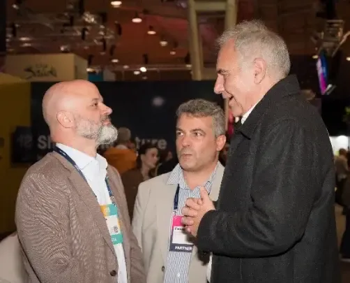 Tres hombres conversan en un pasillo del Web Summit